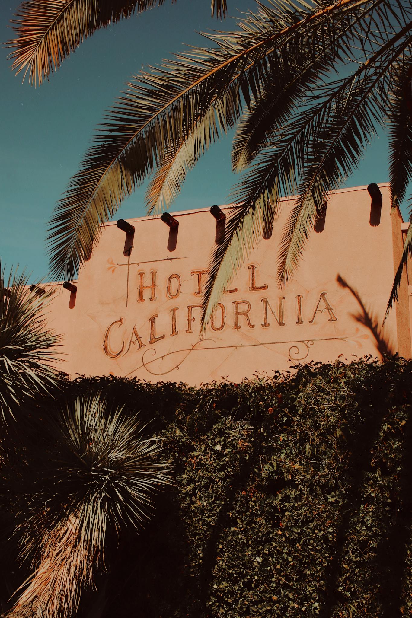 Iconic Hotel California exterior and palm trees in Palm Springs, captured at sunset.