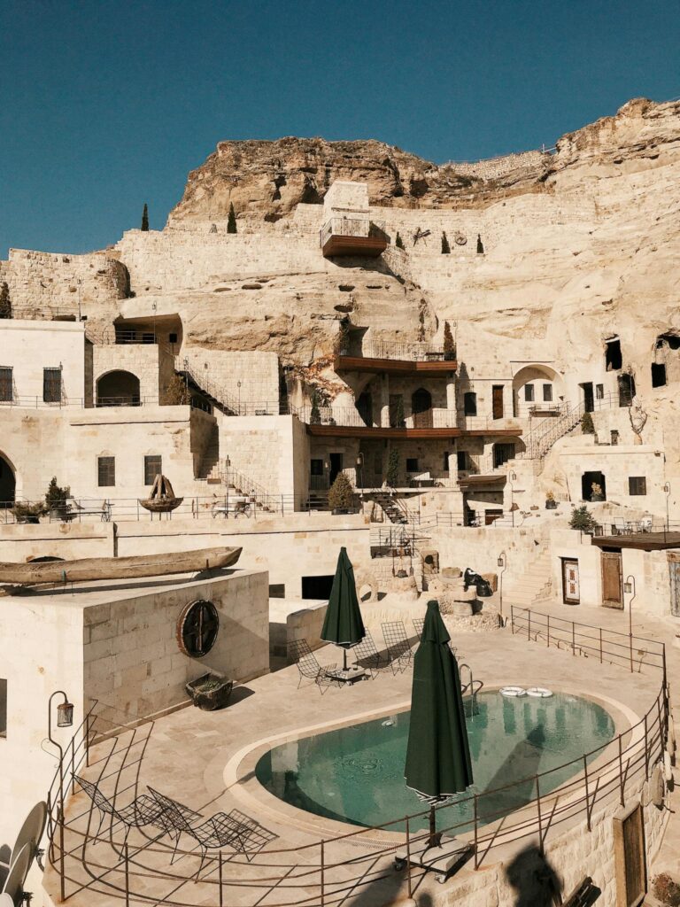 Stunning Cappadocia resort with pool, showcasing unique rock formations and architecture.